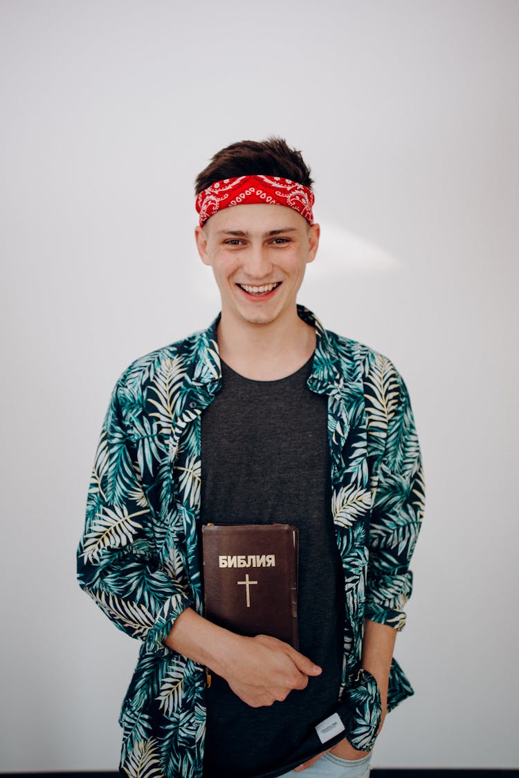 A Man In Floral Long Sleeve Shirt Holding A Bible