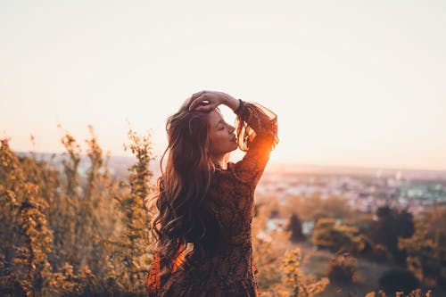 Carefree woman with hand on head standing on hill