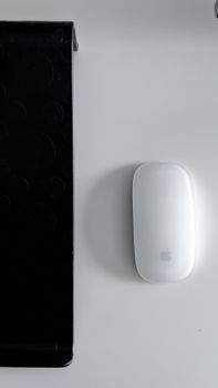 A sleek white computer mouse placed on a white surface beside a black keyboard. Ideal for tech and modern workspace themes.