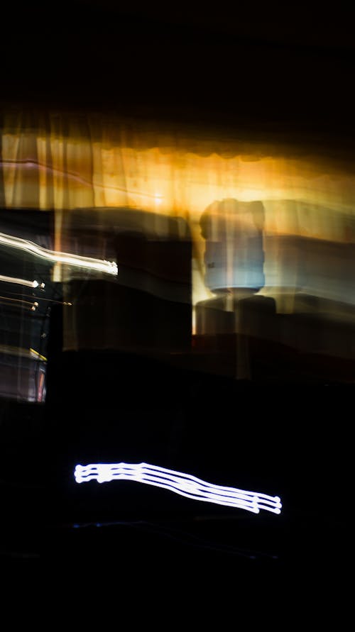 Long exposure of glowing white and yellow neon lights illuminating in darkness against black background