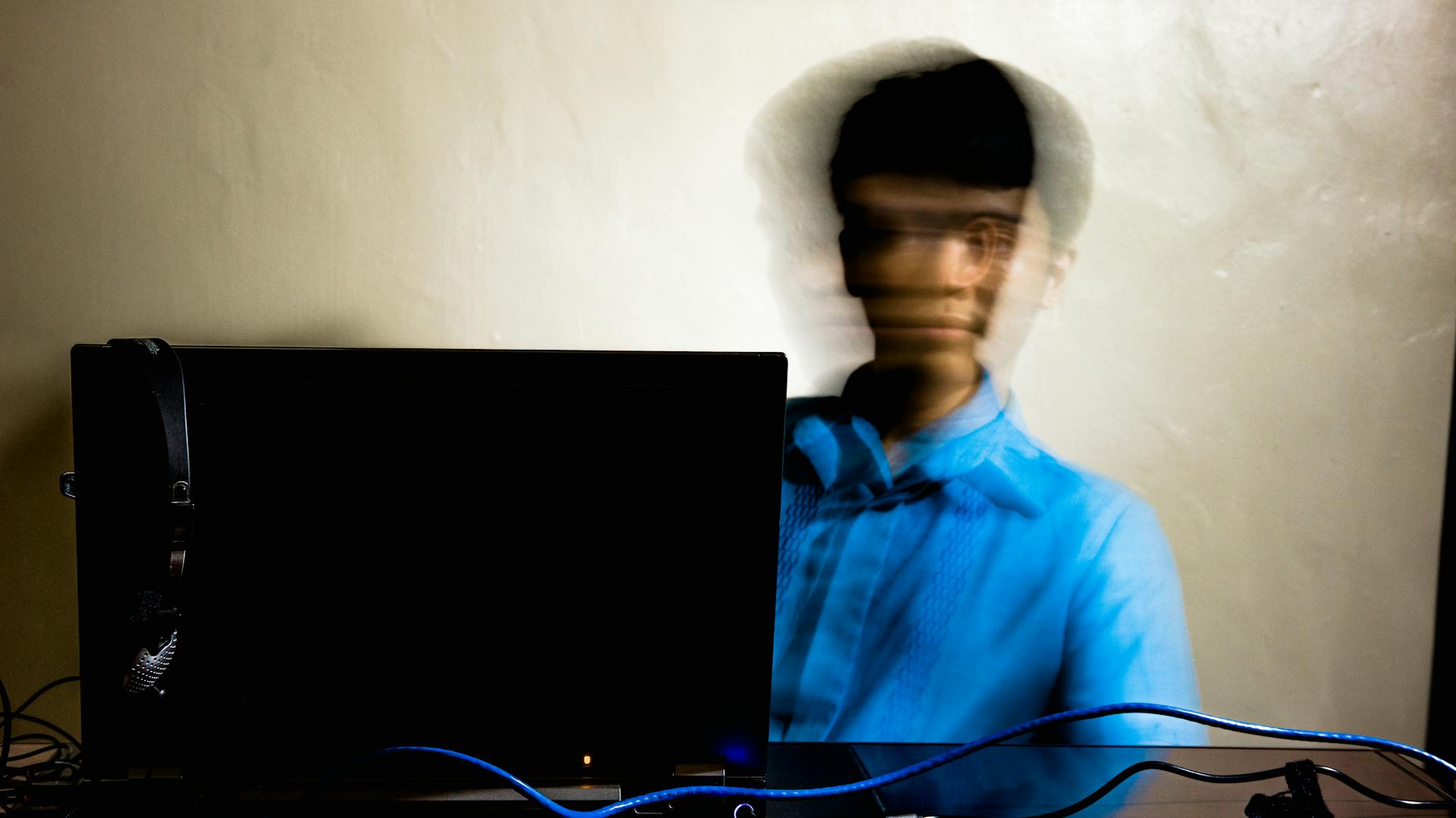 A man with blurred motion is working at his computer, conveying a sense of speed and concentration.