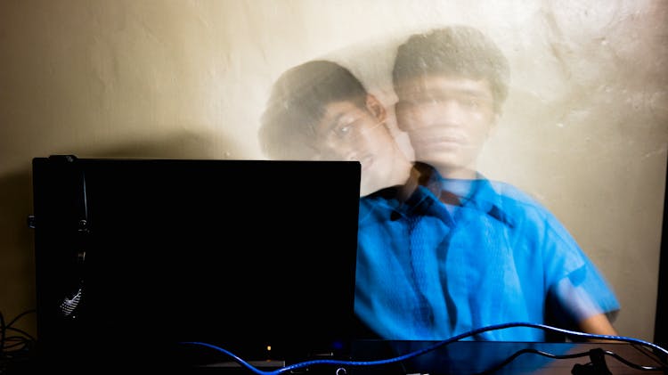 Asian Male Bending Aside Near Laptop Against Yellow Wall