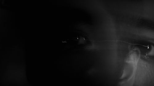 Free Crop face of black eyed person looking at camera in darkness in long exposure Stock Photo