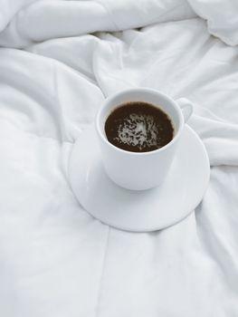 A simple coffee cup with dark brew on a soft, white linen, conveying calm and simplicity.