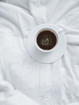 A warm cup of coffee resting on a white blanket, perfect for a cozy morning.