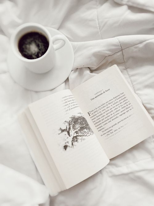 Free An open book and a cup of coffee on white linen, creating a cozy reading ambiance. Stock Photo