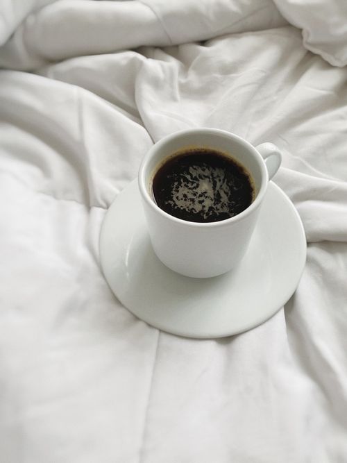 Free Relaxing cup of black coffee on a soft white blanket, perfect for a cozy morning. Stock Photo