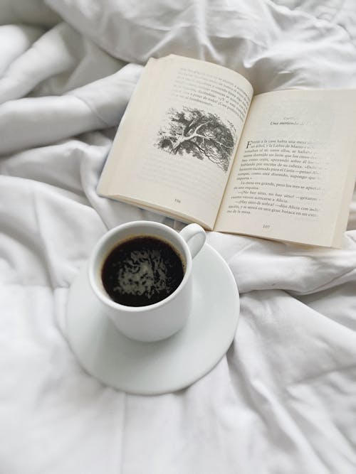 Free An Open Book Beside a Cup of Coffee Stock Photo
