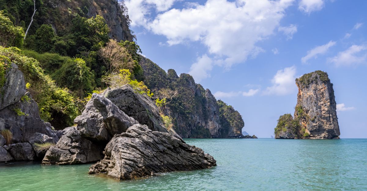 Rock formations and cliffs along a Thai beach with clear water