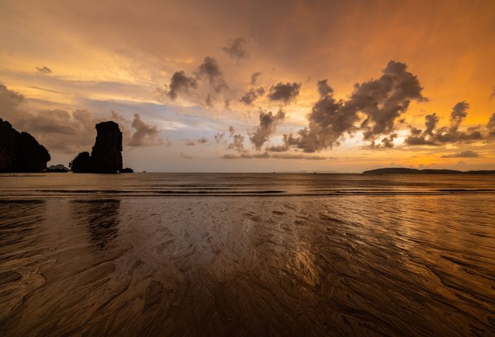 Breathtaking sunset over Ao Nang Beach with vibrant skies and rocky silhouettes.
