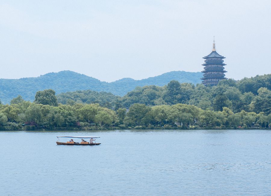 Peaceful scene featuring a boat on West Lake with Leifeng Pagoda in Hangzhou, China.