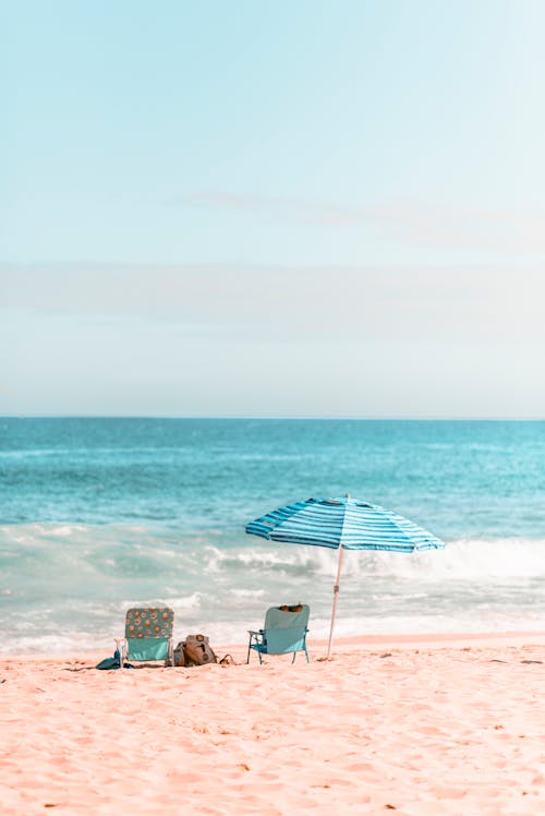 Free Chairs and Umbrella on Beach Shore Stock Photo
