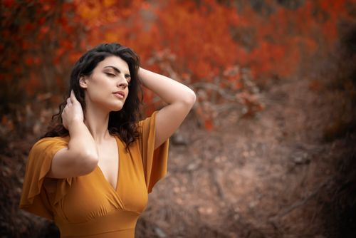 Free A woman in an autumn forest poses gracefully, surrounded by vivid fall foliage. Stock Photo