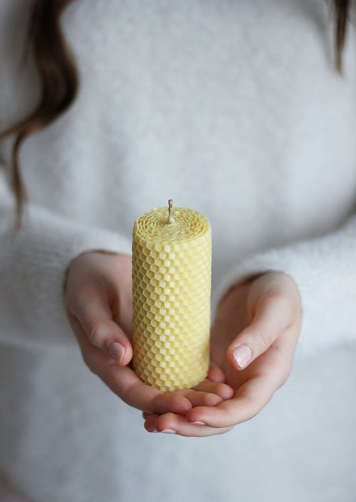 Free A close-up of hands holding a natural beeswax candle, showcasing texture and warmth Stock Photo
