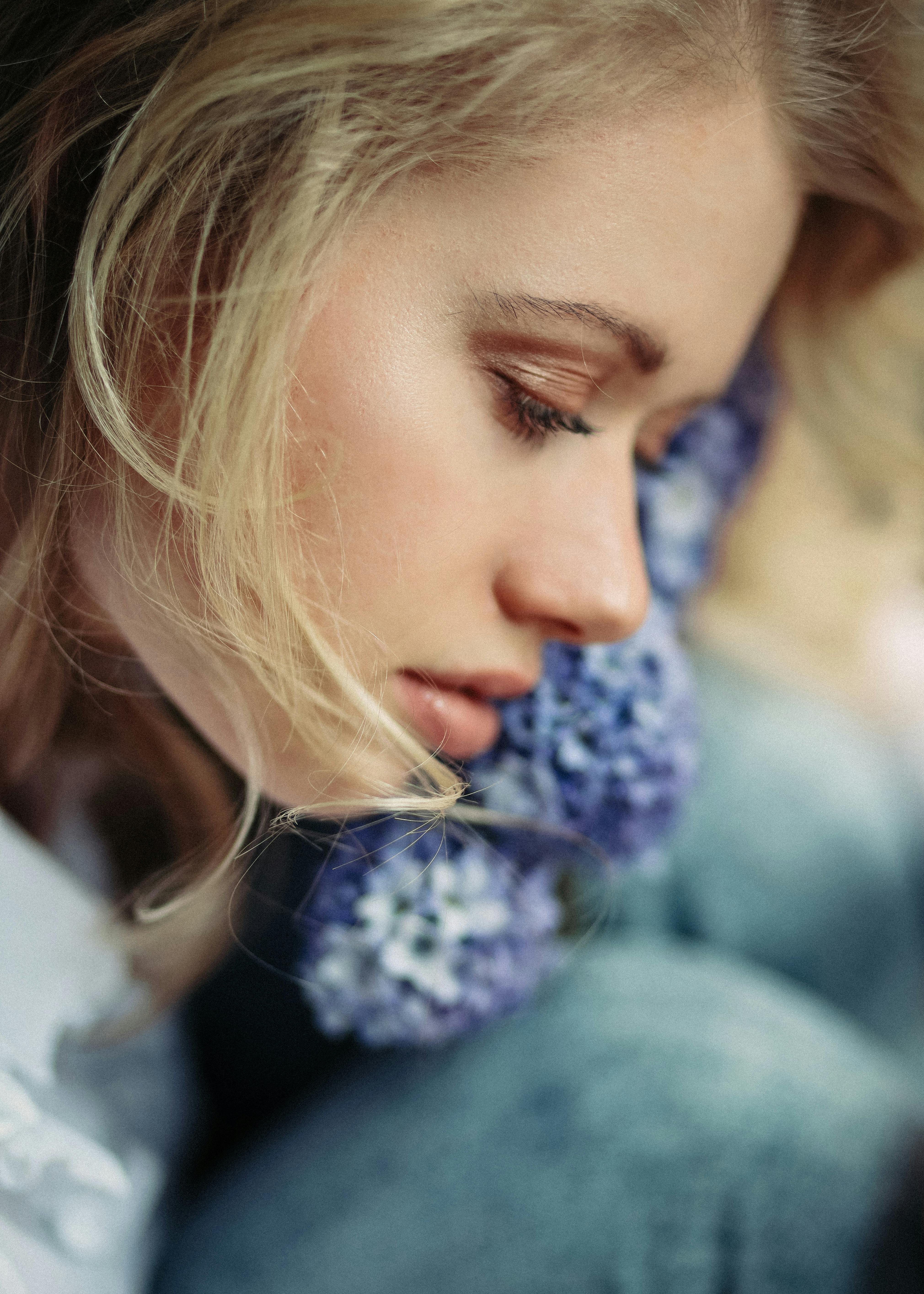 Close-up of a woman with closed eyes and lavender flowers, exuding tranquility.
