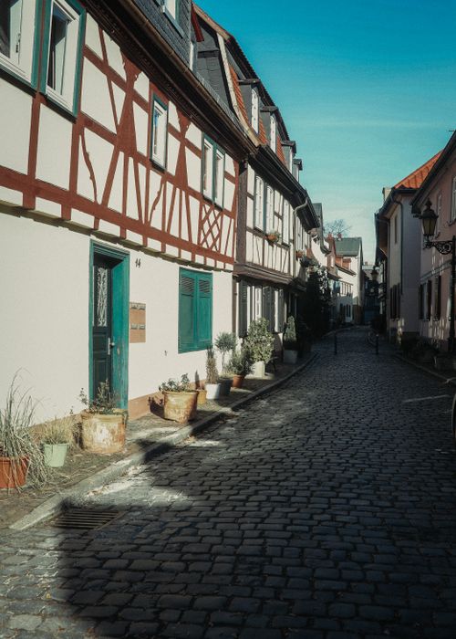 Free Empty cobblestone street between dwelling buildings located in old town district under cloudless blue sky Stock Photo