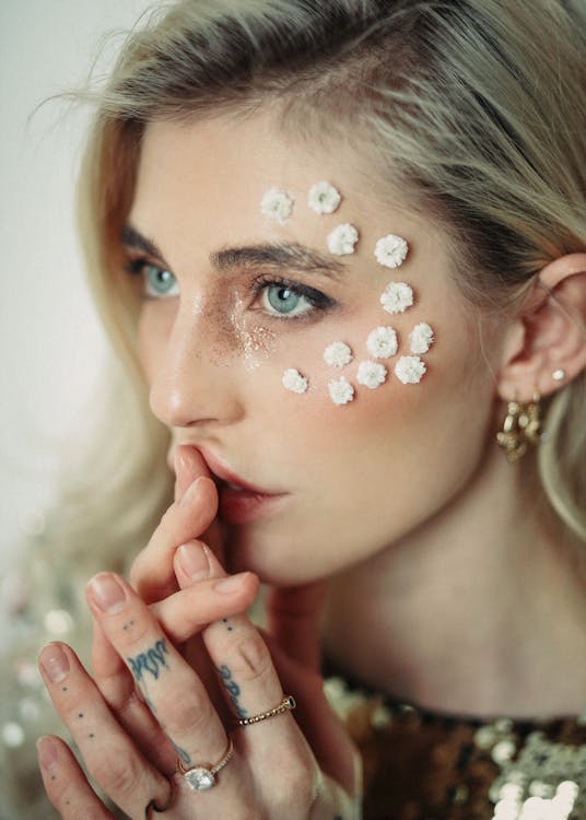 Stylish woman with floral accessories on face