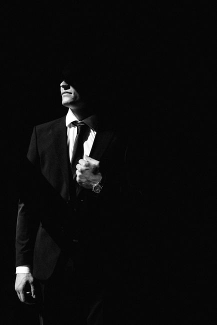 A striking black and white portrait of a man in a suit, exuding confidence and mystery.