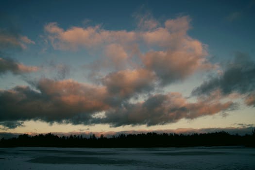 日落时分，巨大的云层在平静的湖面上营造出宁静的氛围，映衬着树木的剪影
