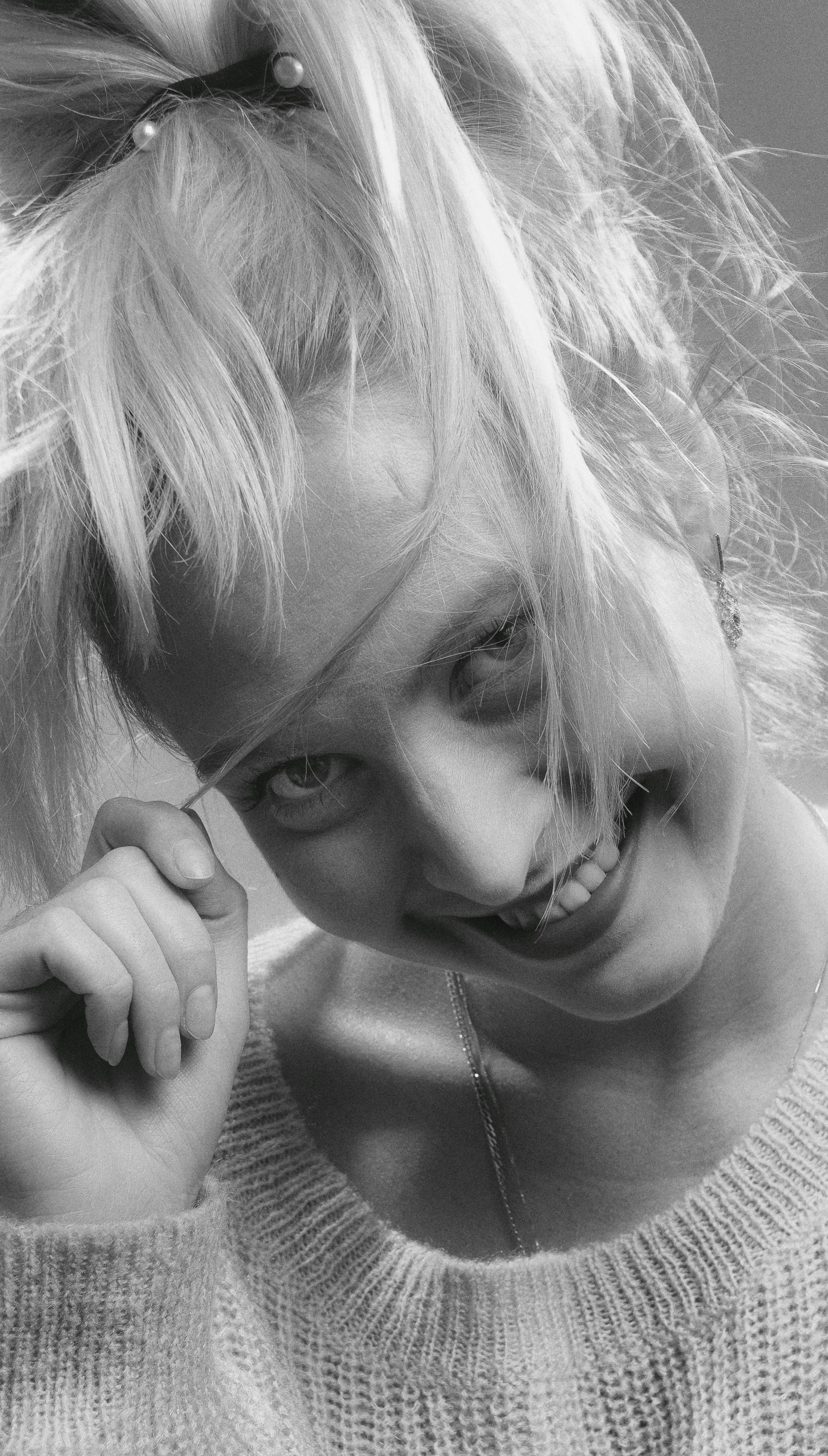 Joyful close-up headshot of a smiling woman in grayscale, emphasizing her playful expression.