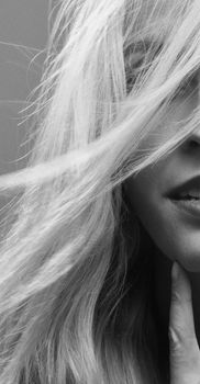 A close-up black and white portrait of a woman with windblown hair, capturing elegance and mystery.