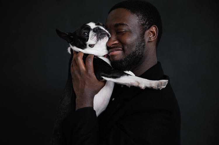 Black Man Hugging Dog Near Black Wall