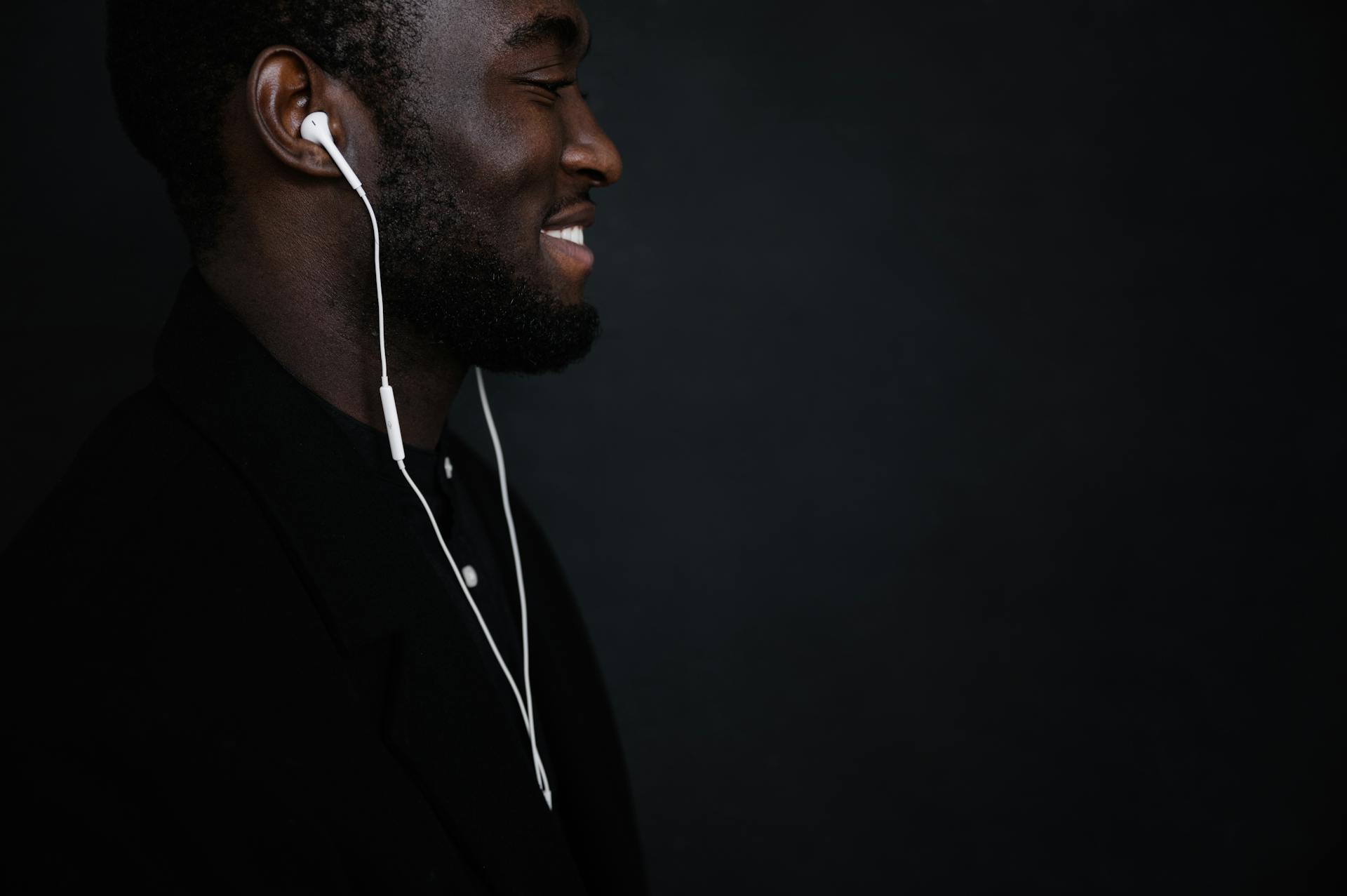 Crop black man with earphones listening to music