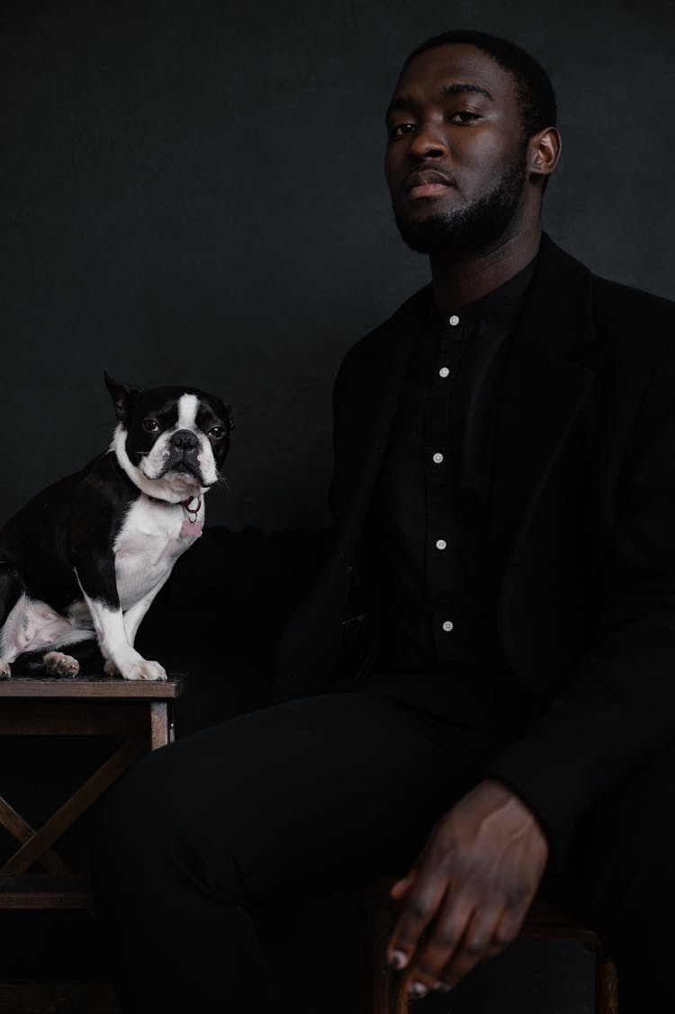 Black Man Sitting Next To Dog On Chair