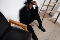 Black man in hat sitting on floor
