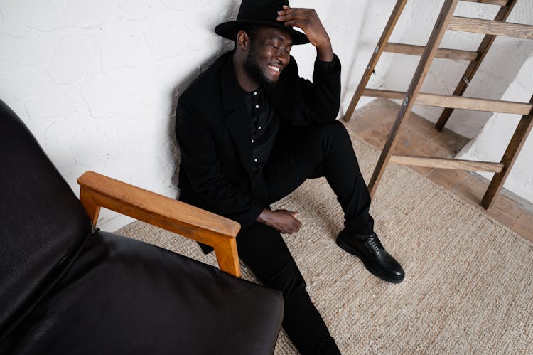 Black Man In Hat Sitting On Floor