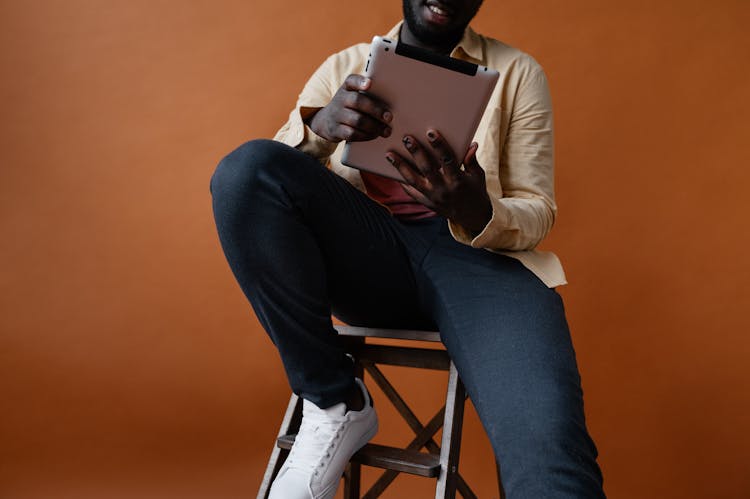 Crop Black Man With Tablet Sitting On Chair