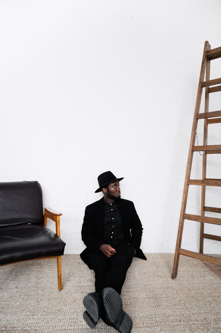 Stylish Black Man In Classy Outfit Sitting On Floor