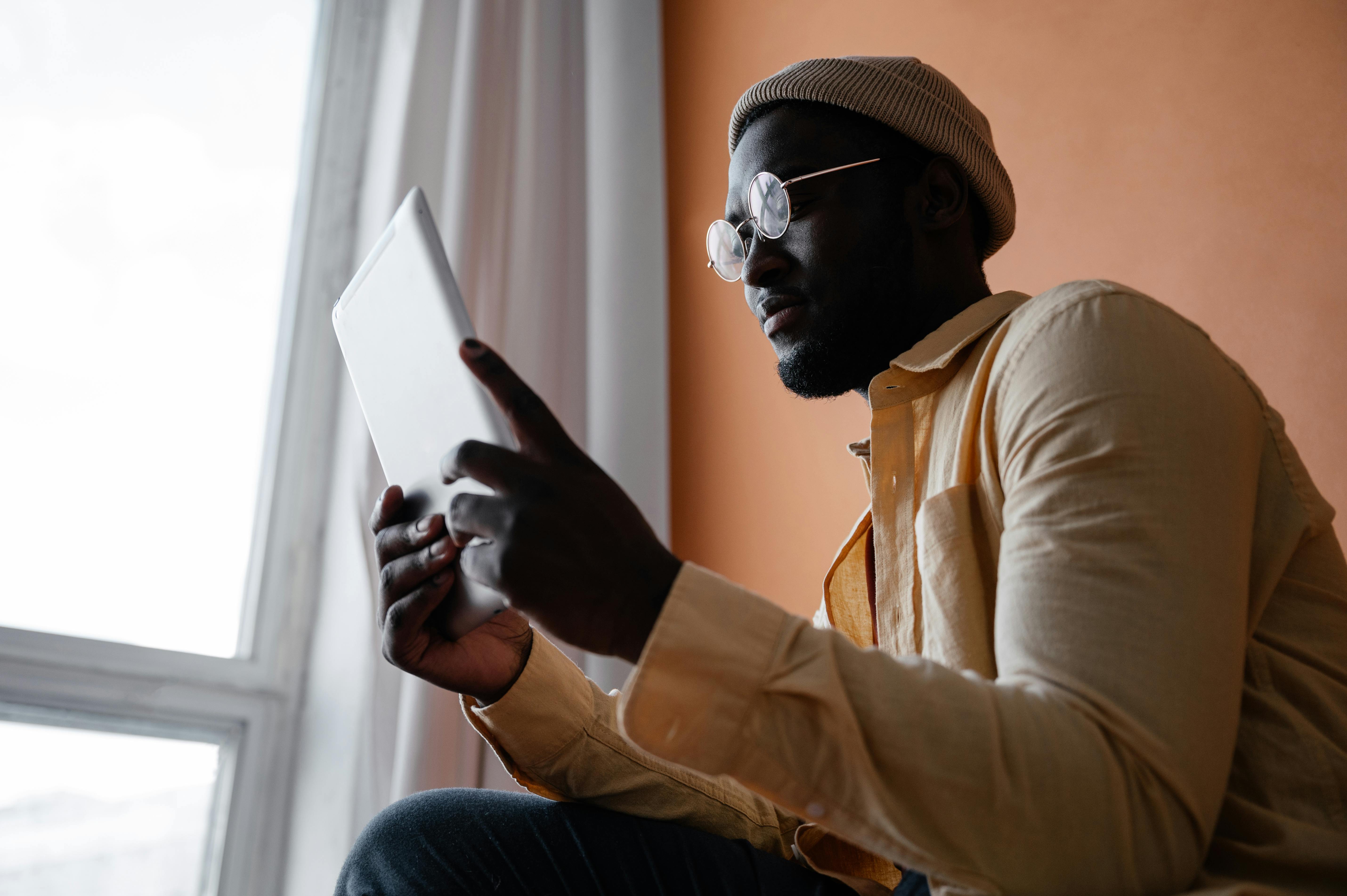 black man with tablet near window