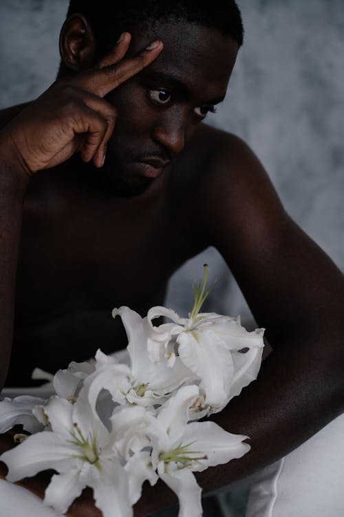 Thoughtful black man with lily flowers