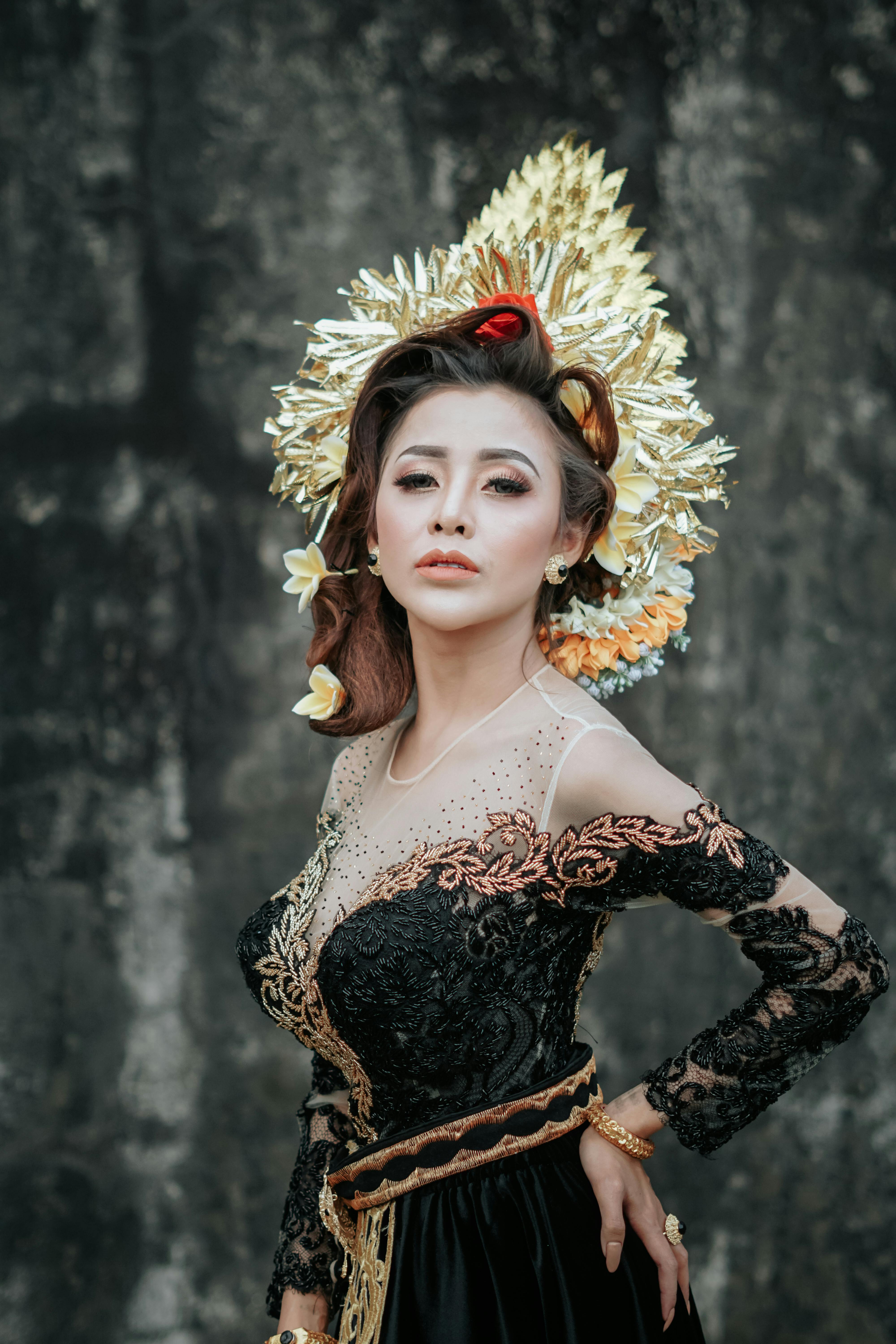 Portrait of a woman in an elegant black lace dress with ornate headdress, posing confidently.