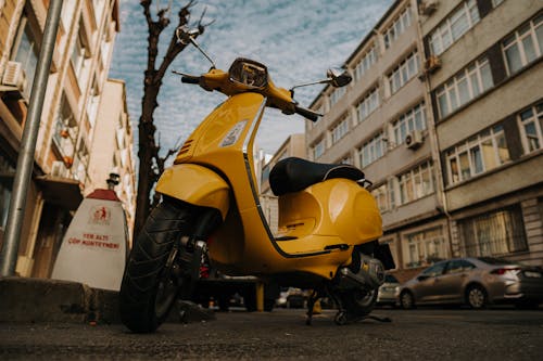 Free A Yellow Motor Scooter Parked on the Road Stock Photo
