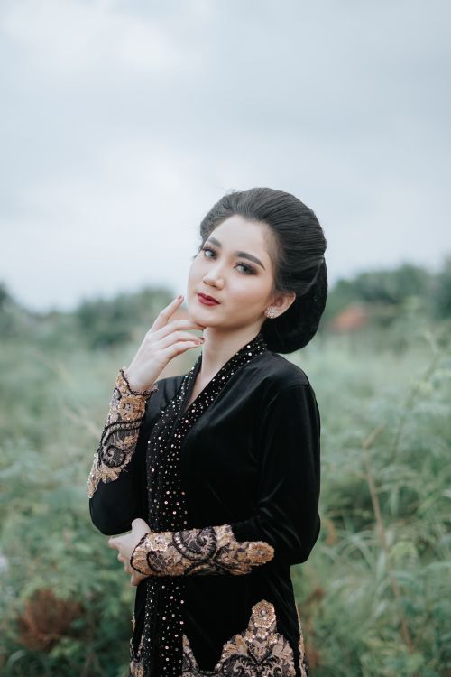 Free A woman in traditional Asian clothing posing gracefully in a lush outdoor setting. Stock Photo