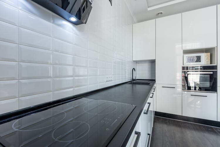 White Kitchen With Black Counter And Built In Appliances