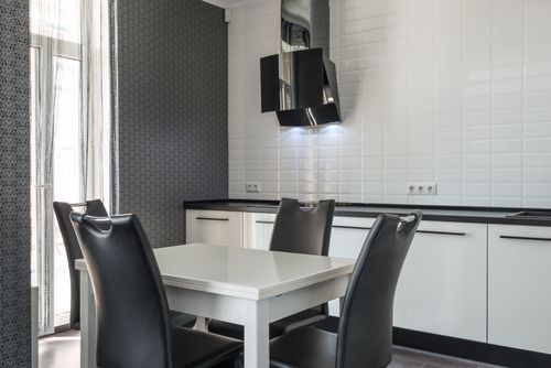 Free Interior of modern black and white kitchen furniture with white cupboards and diner table with black chairs near white tiled wall Stock Photo