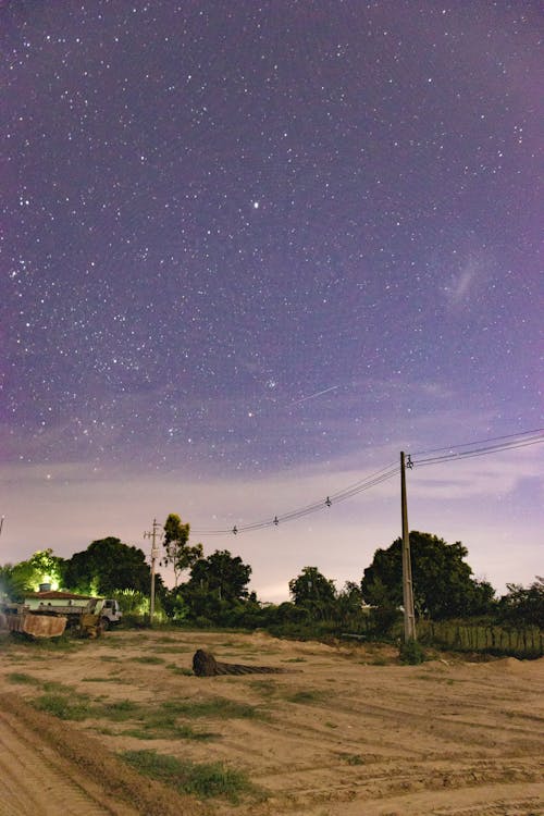 Uncultivated Field in a Village and Purple Sky with Stars