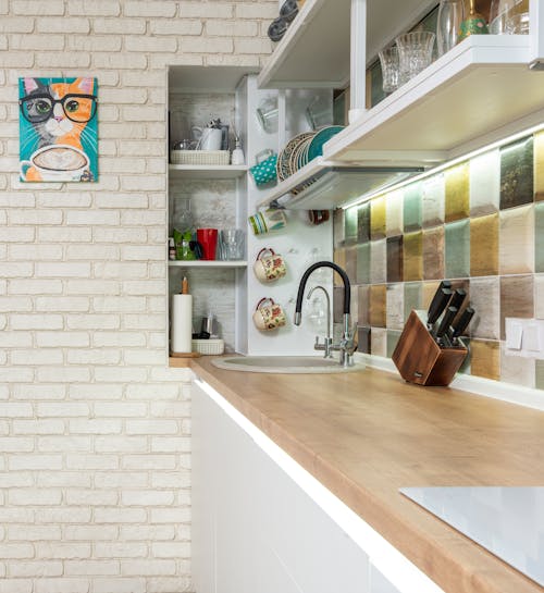 Stylish kitchen counter with various dishware on shelves near sink