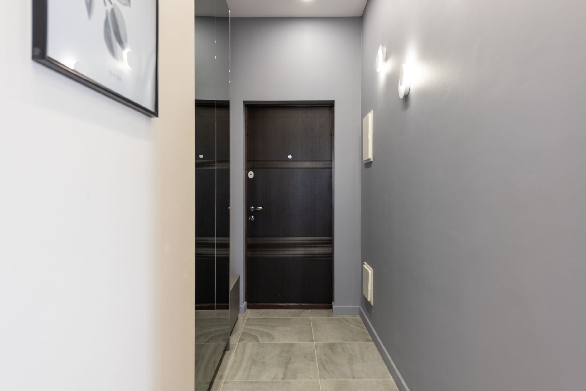 Interior of light empty hallway with white walls and parquet floor furnished with closet with mirror doors
