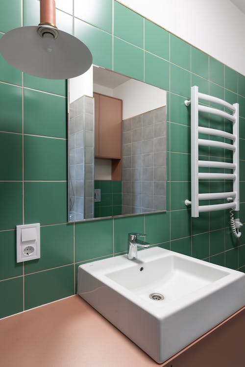 White ceramic sink on pink table and mirror on green wall in contemporary bathroom in new flat