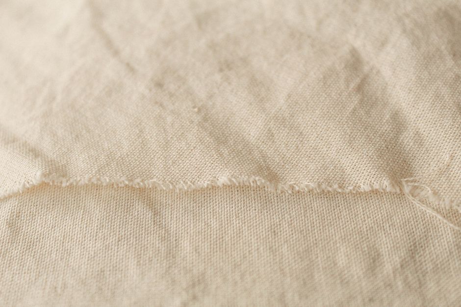 Detailed close-up of soft beige fabric showing texture and stitching.