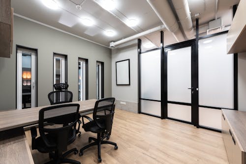 Wooden table and black office chairs placed in spacious room in new contemporary workplace
