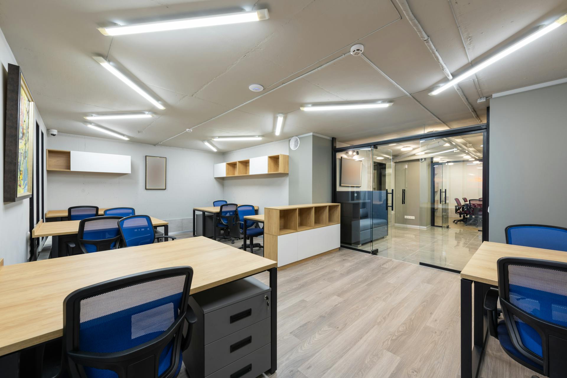 Spacious modern office interior with wooden desks, blue chairs, and ample lighting.
