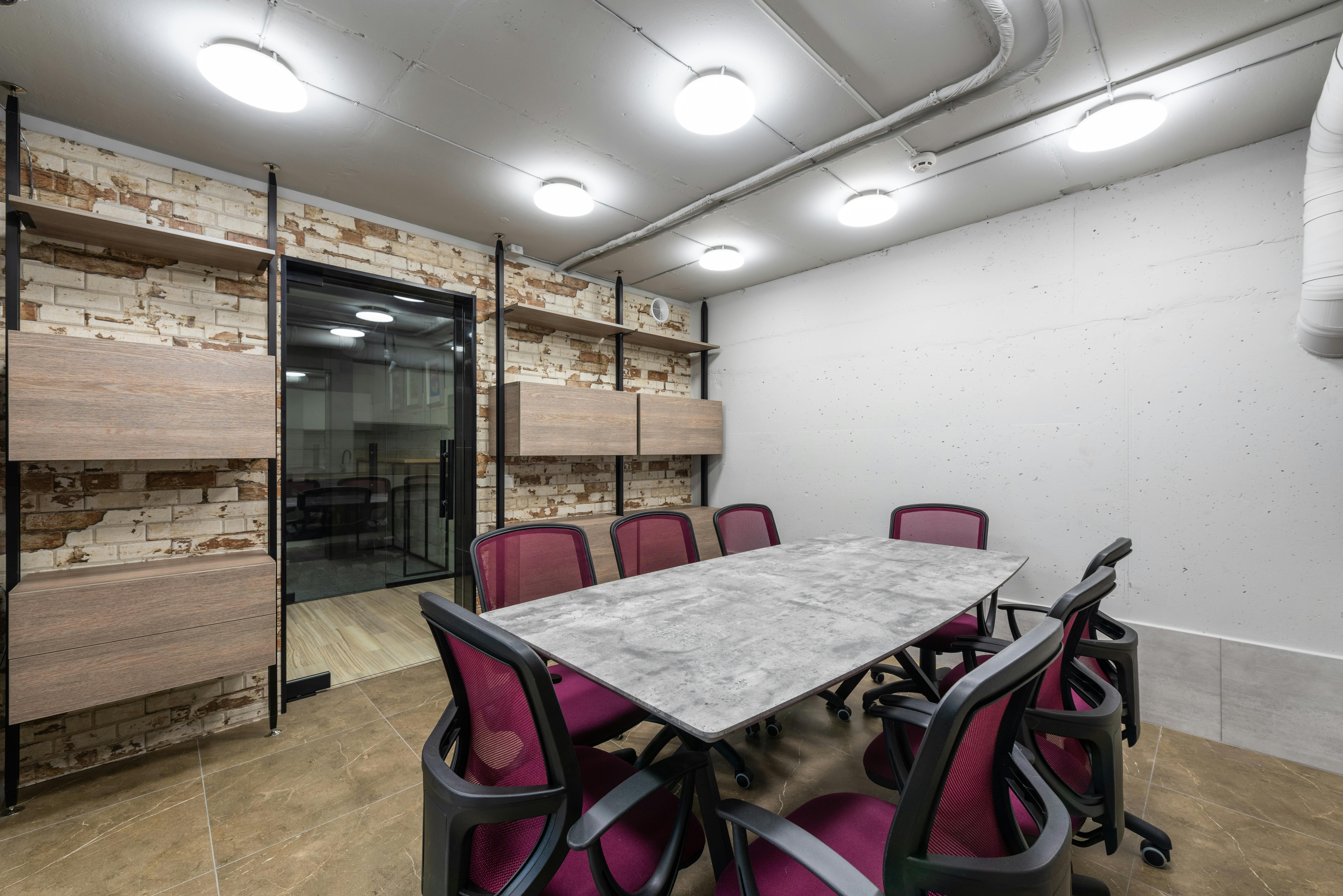 Interior of boardroom with wooden table and office chairs under ceiling with glowing lamps in workspace