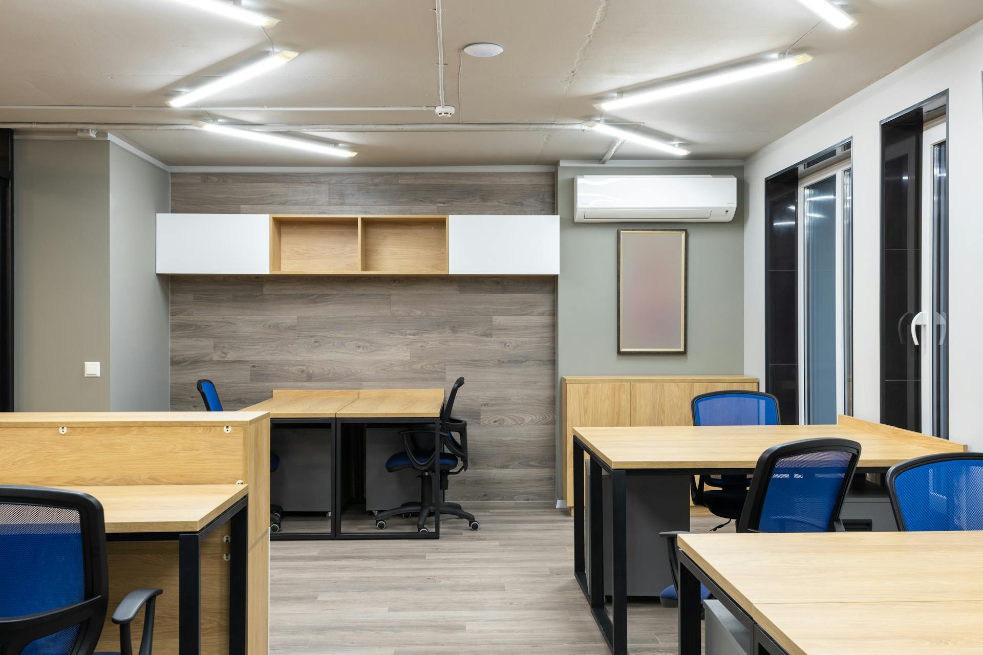 Spacious and modern office interior with wooden desks and blue chairs.