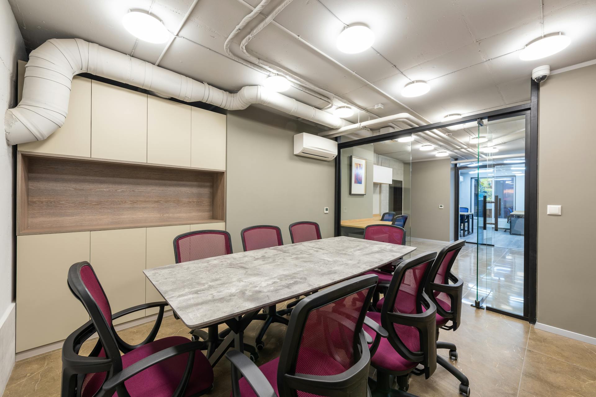 Spacious boardroom with modern decor, featuring glass walls, sleek furniture, and vibrant chairs.