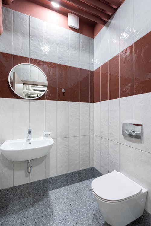 Modern interior of new clean bathroom with white toilet and ceramic sink under ceiling with lamp